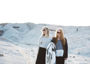 Two women wearing colorful Noz and sunglasses in the sand. 